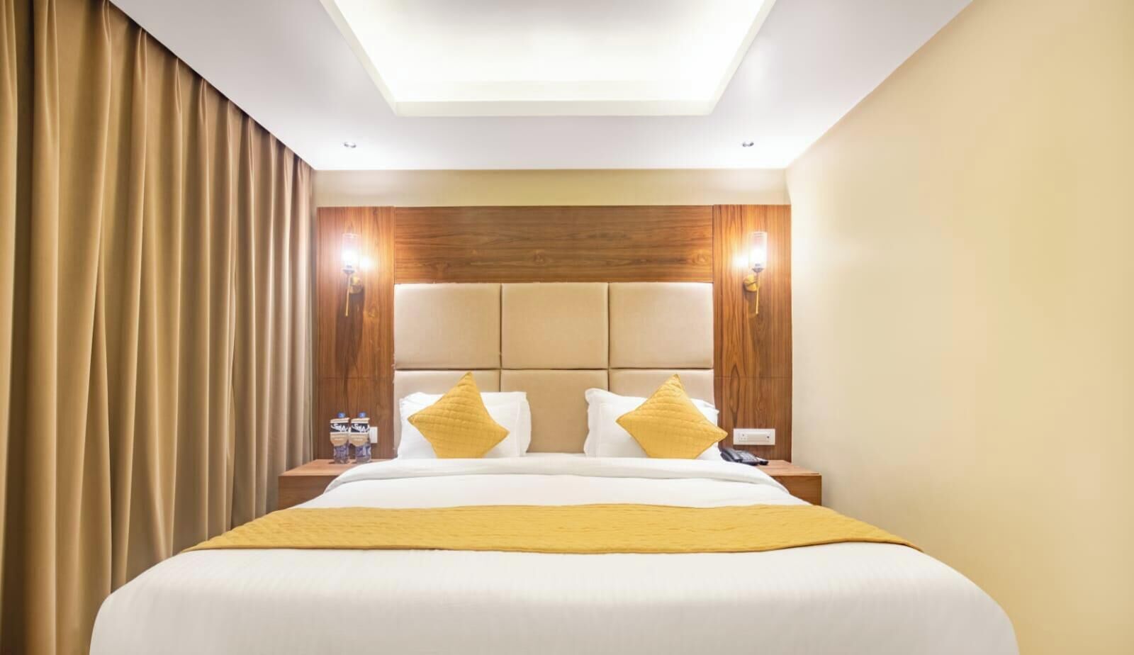 A hotel room with a large bed, wooden headboard, two bedside tables, and a ceiling light.