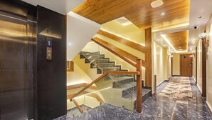A modern hotel interior with a marble staircase, wooden ceiling, and a glass elevator. - Sondermall Palace (Srinagar)
