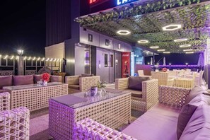 An outdoor seating area with wicker furniture and a Coca-Cola advertisement. - Sondermall Palace (Srinagar)