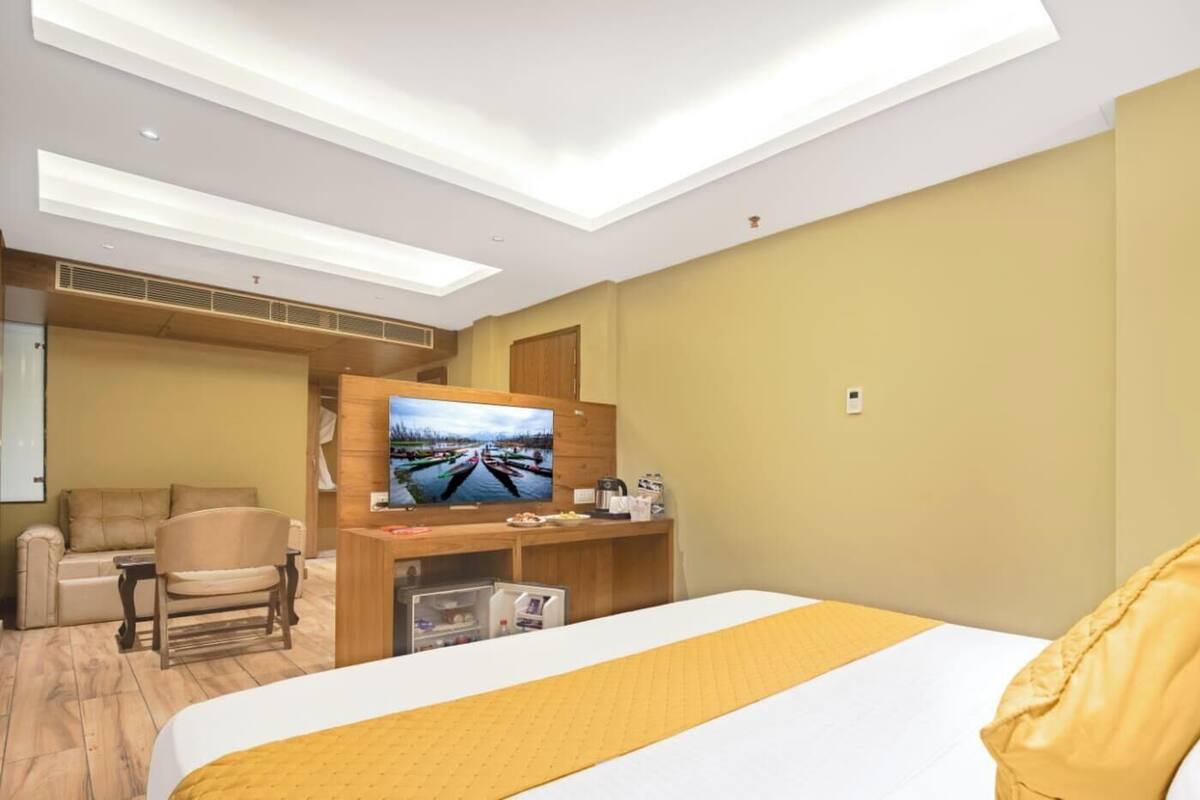 A hotel room with a bed, a TV, a sofa, and a desk with a computer.