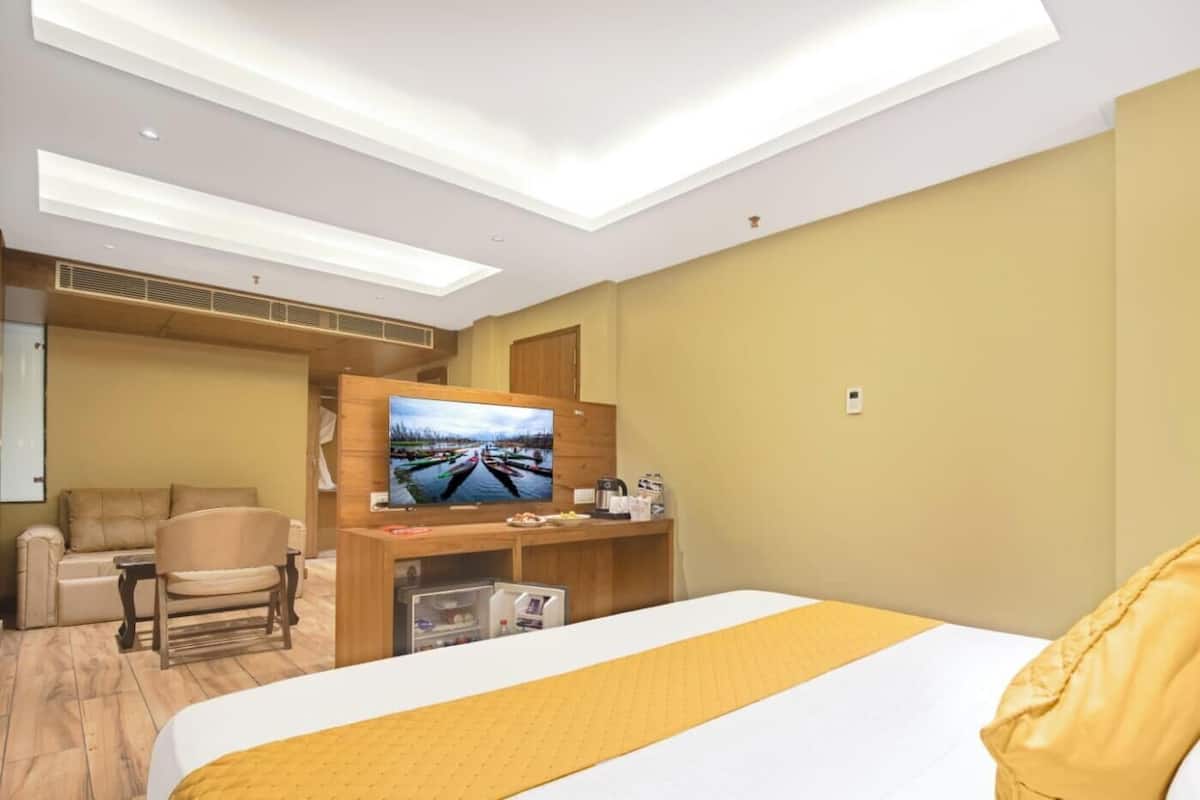 A hotel room with a bed, a TV, a sofa, and a desk with a computer.