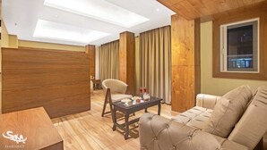 A modern living room with a sofa, a dining table with a chair, and a view of the city at night through a window. - Sondermall Palace (Srinagar)