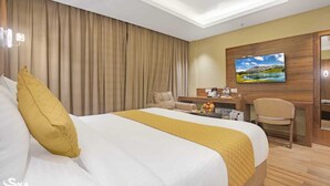 A hotel room with a large bed, a desk, a chair, and a television on the wall. - Sondermall Palace (Srinagar)
