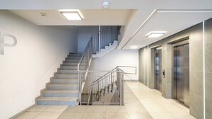 Et moderne interiør med trappe, elevatorer og bogstavet 'P' på væggen.