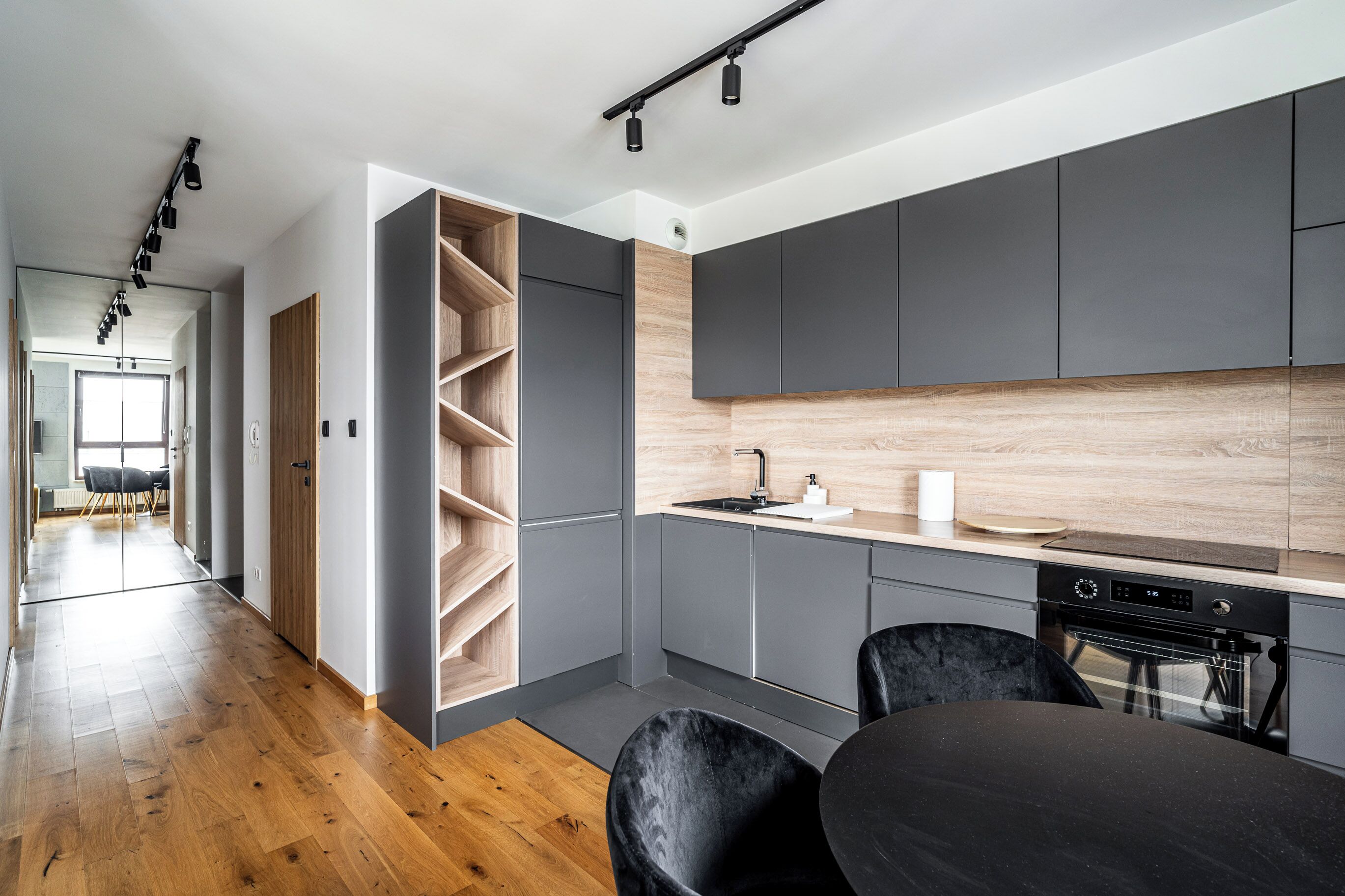 Una cocina moderna con armarios grises, encimera de madera y horno empotrado.