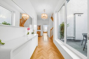 A hallway with a wooden floor, white walls, a staircase, and a dining area visible in the distance. - 140qm, 3 Bedrooms, city center, 3 terraces, AC (Wien)