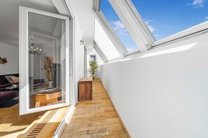 A narrow hallway with wooden flooring, a glass door leading to a room with a chandelier, and a small wooden table. - 140qm, 3 Bedrooms, city center, 3 terraces, AC (Wien)