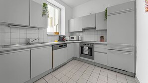 Een moderne keuken met witte kastjes, een ingebouwde oven en een magnetron.