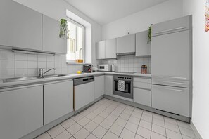 A modern kitchen with white cabinetry, a built-in oven, and a microwave. - 140qm, 3 Bedrooms, city center, 3 terraces, AC (Wien)