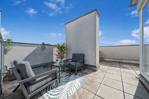 A rooftop terrace with a sofa, armchair, and a small table with a vase of flowers. - 140qm, 3 Bedrooms, city center, 3 terraces, AC (Wien)