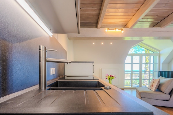 Una cocina moderna con estufa integrada, un lavabo y techo de madera.