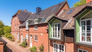 A row of red brick houses with pitched roofs and multiple windows. - Vacation apartment Stöfs - Baltic Sea vacation. Close to the beach. Nature. Lake view. (Behrensdorf)