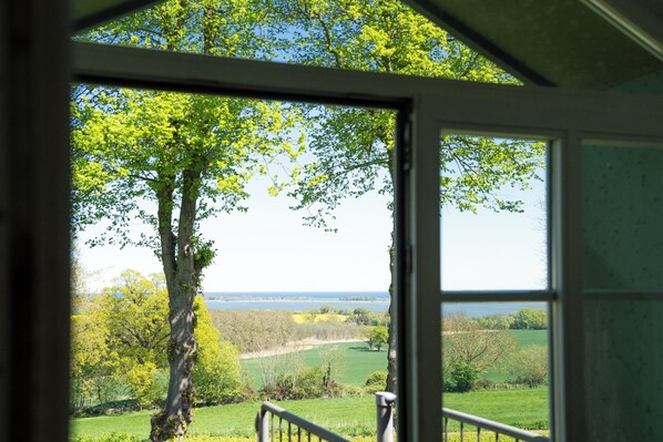 Une pièce dotée d’une grande fenêtre donnant sur un paysage arboré et un plan d’eau.