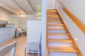 Un intérieur moderne comprenant un escalier, un coin repas et une cuisine.
