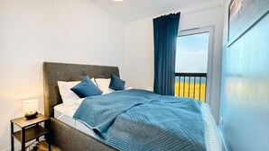 A bed with a grey headboard, white bedding, and blue pillows. - Lake view apartment Dziwnow (Dziwnów)