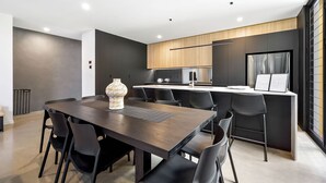 Una cocina moderna con una isla central, sillas negras y un jarrón decorativo.