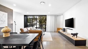 Una sala de estar moderna con sofá, televisor y comedor.