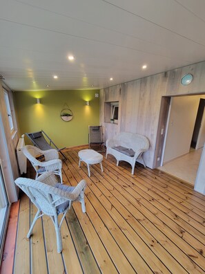 Une pièce avec un plancher en bois, des meubles en osier et un mur vert.