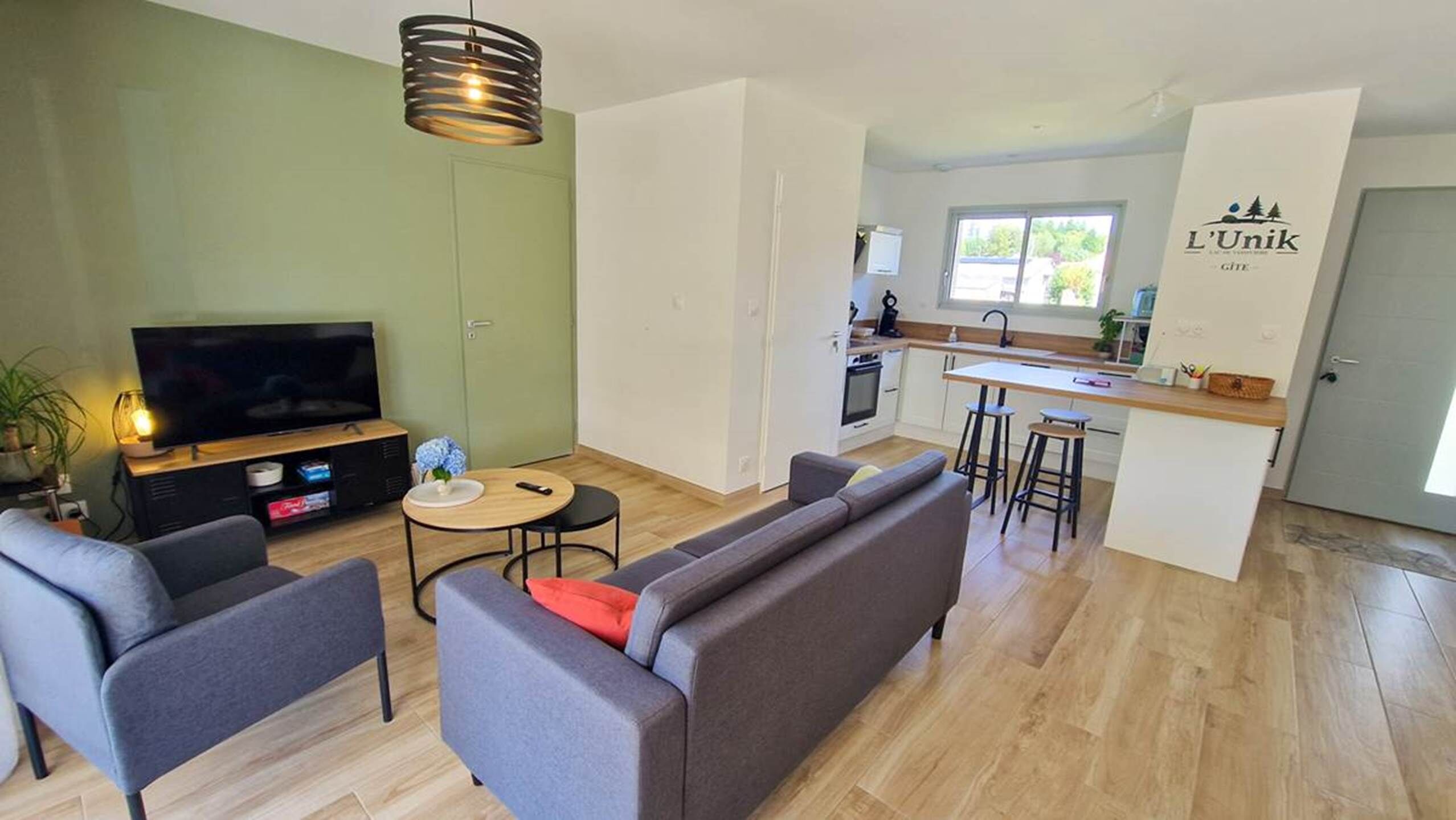 Een moderne woonkamer met een bank, televisie en een klein tafeltje met een afstandsbediening.