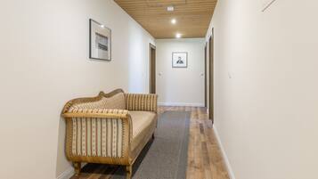A hallway with a wooden ceiling, a sofa, and a rug.