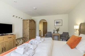Una camera d'albergo con un letto, una televisione, un armadio, una scrivania con sedia e un quadro appeso al muro.