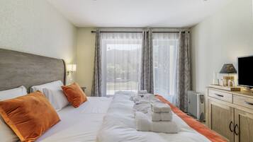 Ein Hotelzimmer mit einem großen Bett, einem Fernseher und Blick ins Freie.
