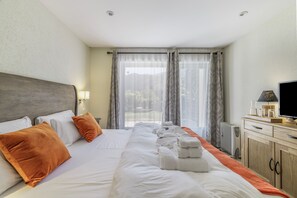 Ein Hotelzimmer mit einem großen Bett, einem Fernseher und Blick ins Freie.