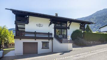 Ein Chalet mit einem Schild, das 'Chalet Bodenschatz' zeigt, einem hölzernen Balkon und einem Berg im Hintergrund.