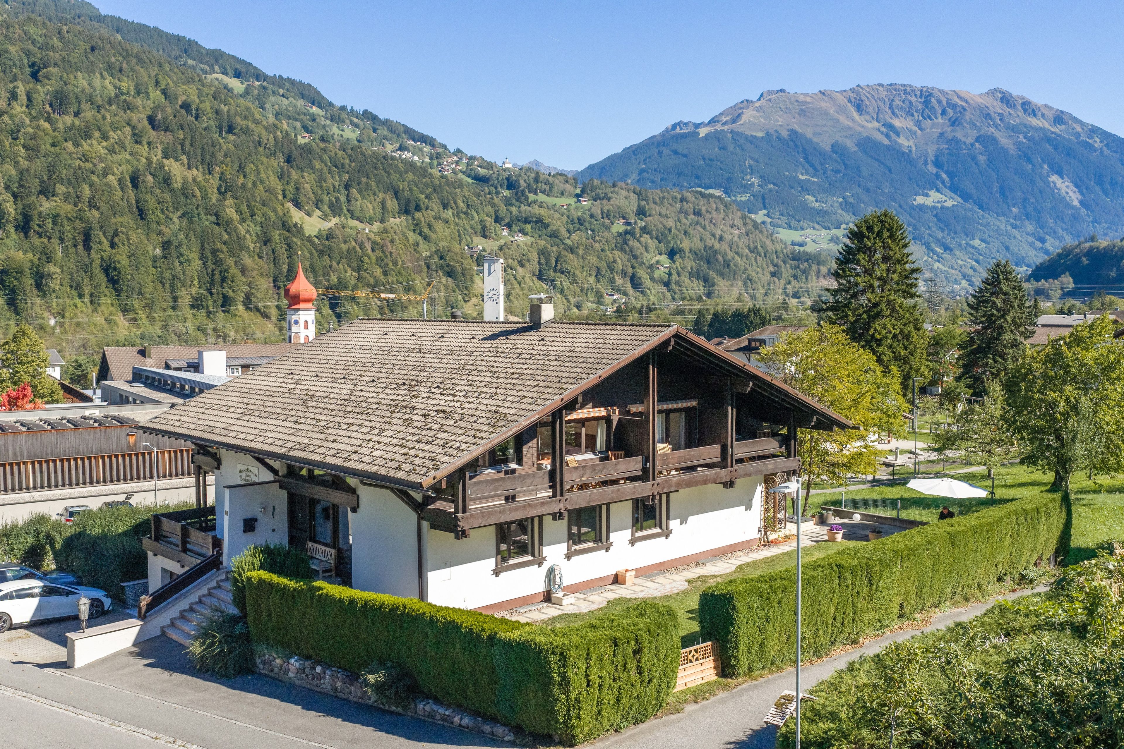 Un bâtiment de style chalet, doté d’un toit en pente, de balcons en bois et offrant une vue sur un paysage montagneux.