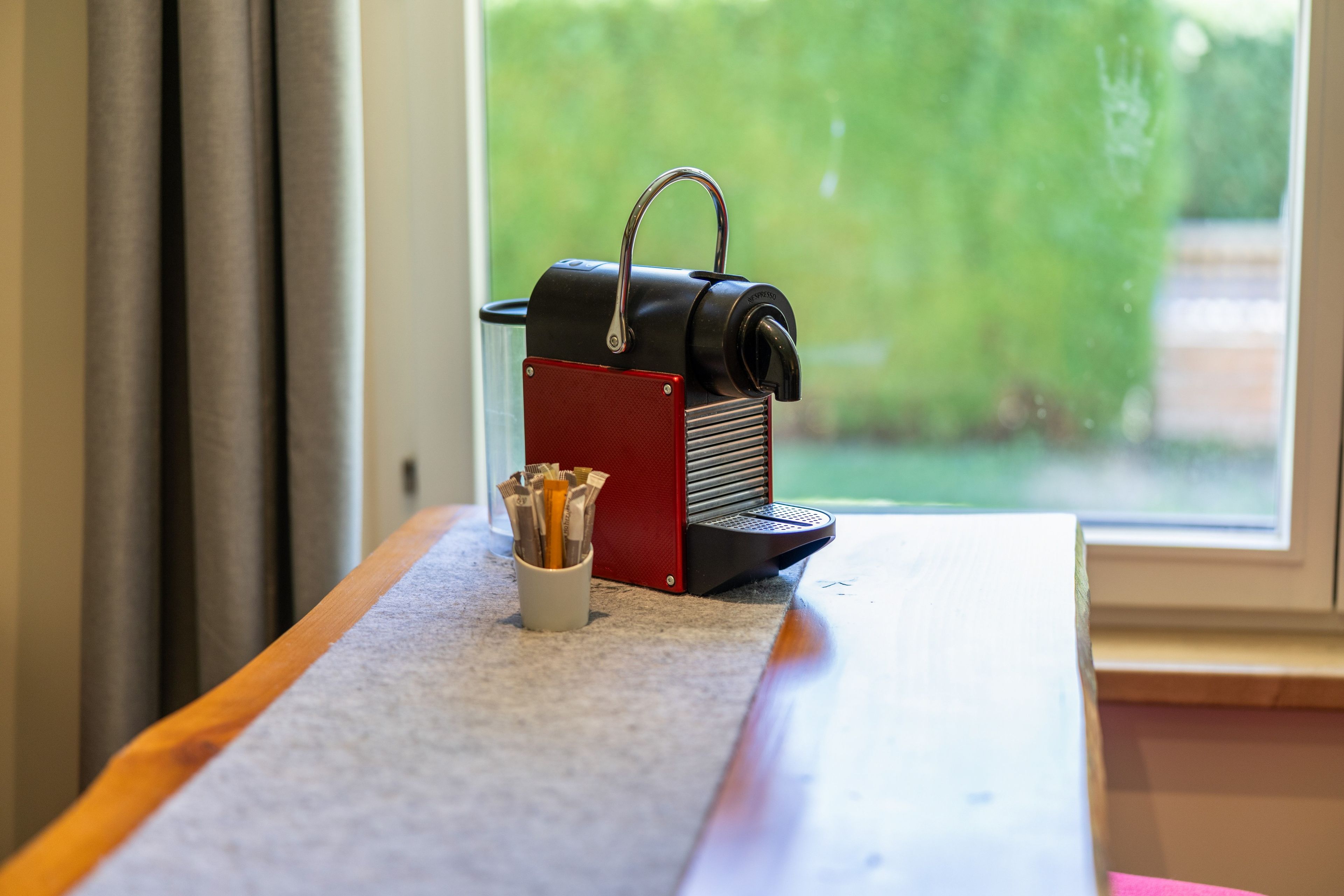 Une machine à café Nespresso est posée sur une table, à côté d’une tasse de capsules de café.