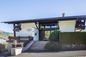 A building with a white facade, wooden staircase, and a sign indicating a chalet. - Chalet Suite with Breakfast, Mountain Views & Private Terrace (Vandans)