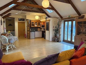 Une cuisine spacieuse avec des meubles en bois, un coin repas avec une table et des chaises, et un salon confortable avec un canapé.