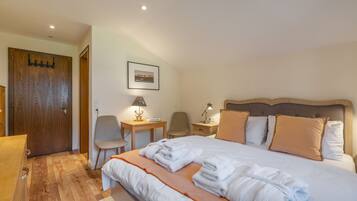 A hotel room with a bed, a desk, a chair, a wooden door, and a framed picture on the wall.