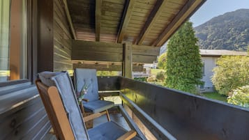 A wooden balcony with a view of a mountain and a house.