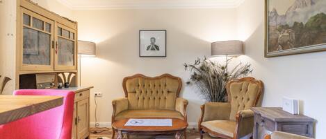 Quarto com armário de madeira, duas poltronas, uma mesa e um quadro na parede.