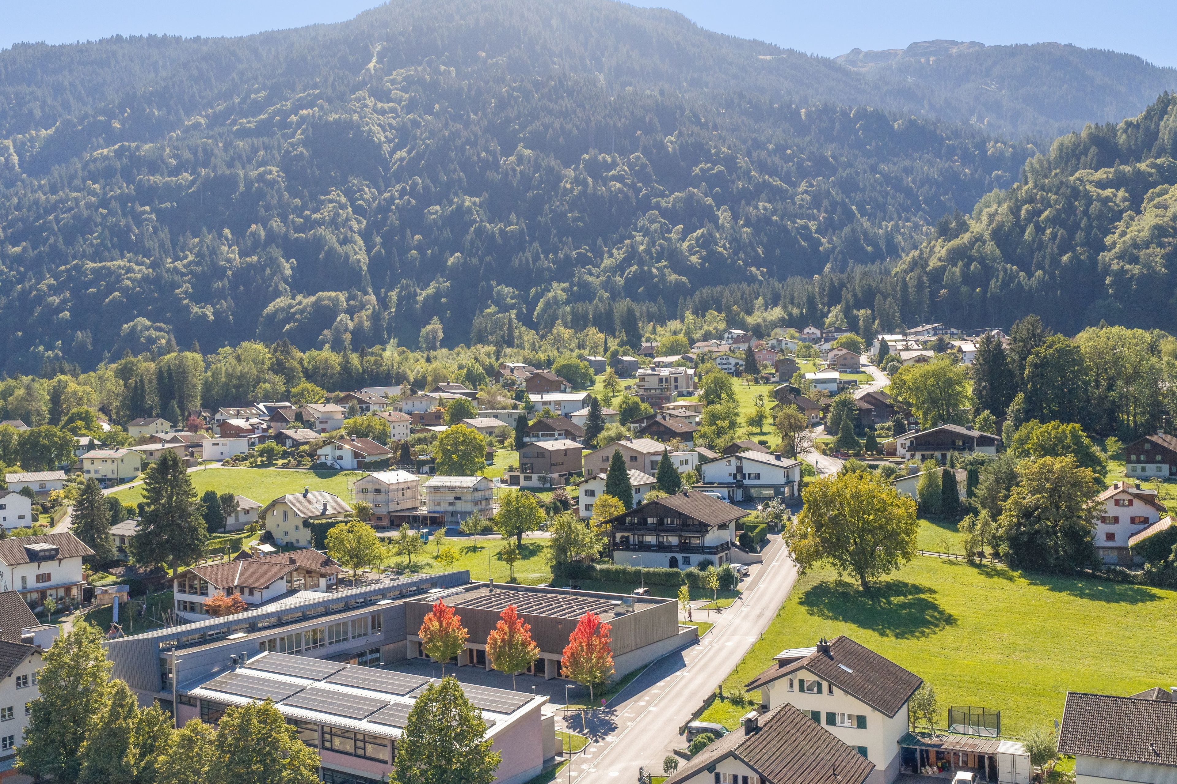 A residential area with houses, a road, and a building with solar panels.