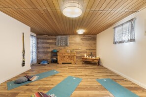 Et yogarum med trægulv, en loftslampe, et træskab og yogamåtter.