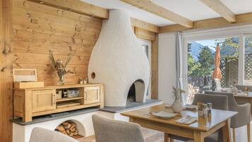 A cozy interior with a wooden wall, a fireplace, a dining area, and a view of the outdoors.