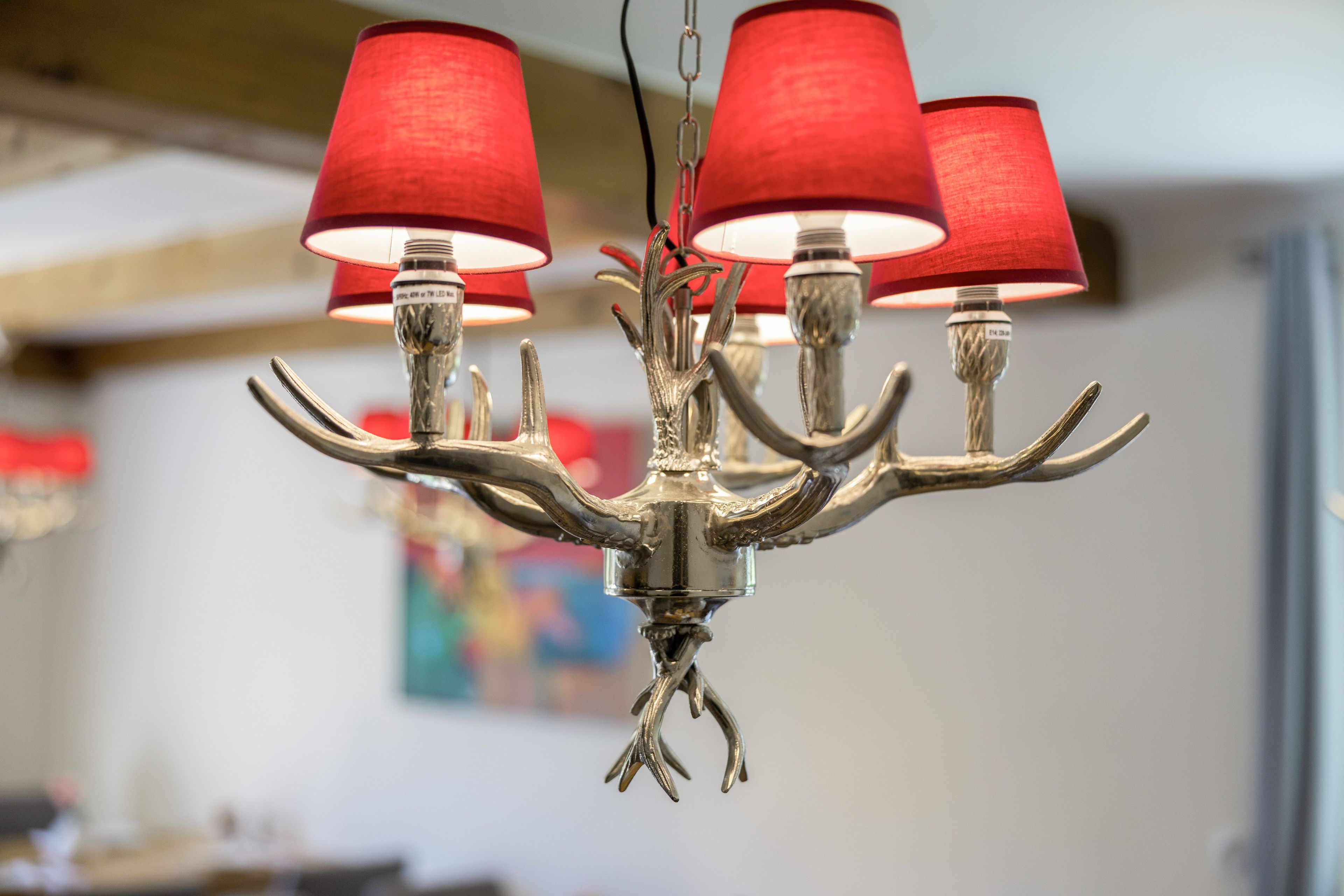 A chandelier with multiple arms and red lampshades.