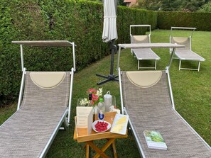 Des fauteuils de jardin disposés en demi-cercle autour d’une table, sur laquelle se trouvent une bouteille, un verre et un menu.