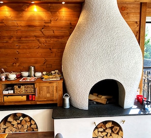 Une cuisine rustique avec un four en pierre, des armoires en bois et un espace de rangement pour le bois de chauffage.