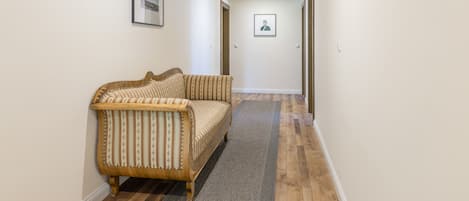 A hallway with a wooden ceiling, a sofa, and a rug.