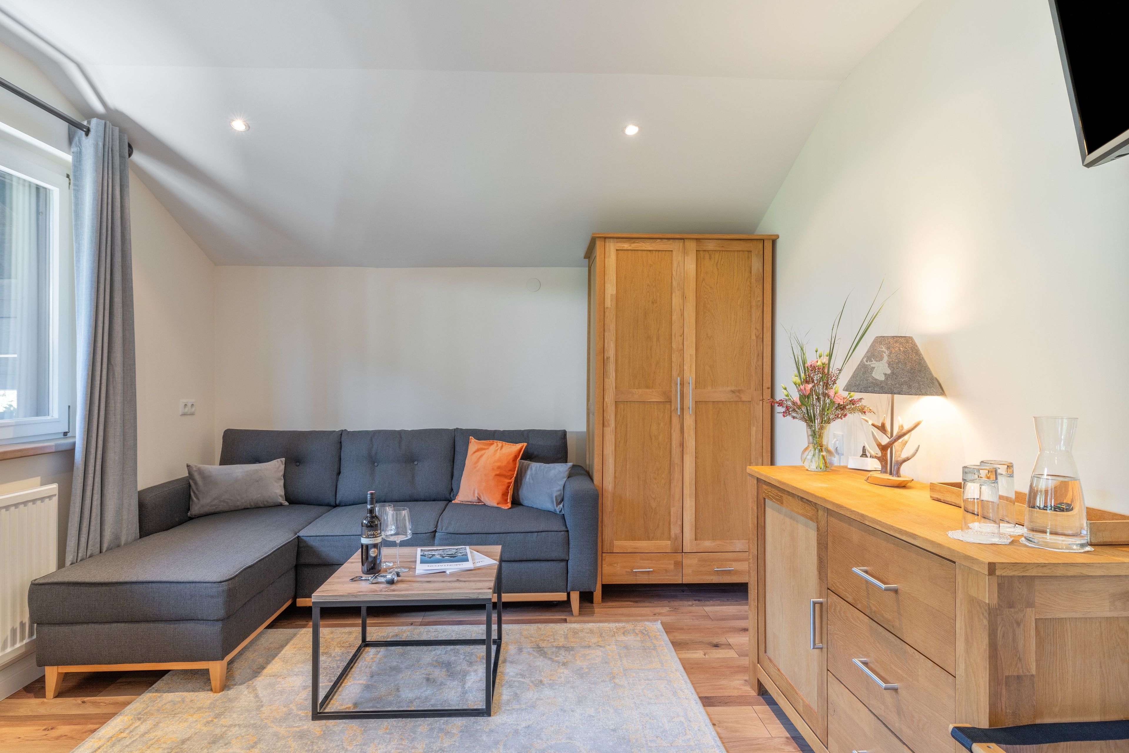 Ein modernes Wohnzimmer mit einem grauen Sofa, einem Holzschrank und einem Couchtisch.