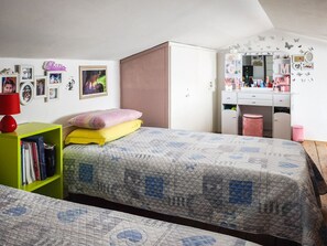 A bedroom with two beds, a wardrobe, a bookshelf, a desk with a mirror, and wall decorations. - Magic DaLu House - Olbia (Olbia)