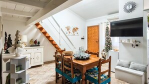 A dining area with a wooden table and chairs, a staircase, a TV mounted on the wall, and a Christmas tree. - Magic DaLu House - Olbia (Olbia)