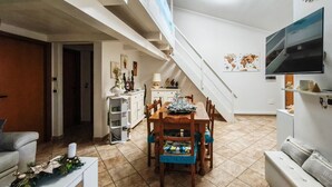 A spacious living area with a dining table, chairs, a sofa, and a staircase. - Magic DaLu House - Olbia (Olbia)
