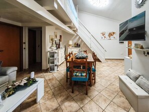 A spacious living area with a dining table, chairs, a sofa, and a staircase. - Magic DaLu House - Olbia (Olbia)