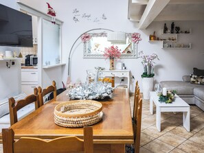 A dining area with a wooden table, chairs, a decorative centerpiece, a white console table, and a sofa in a modern living space. - Magic DaLu House (Olbia)