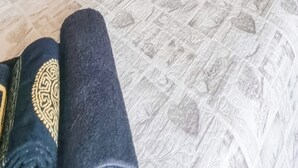Sängyssä on kuviollinen vuodevaatesetti, tekstillä varustetut tyynyt ja rullalle taitettu pyyhe.