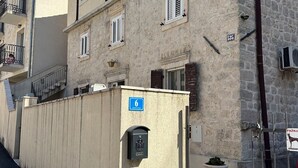 A multi-story building with a stone facade, numbered 6, featuring balconies, a mailbox, and a utility pole. - Studio Apartment Emi Kotor (Kotor)